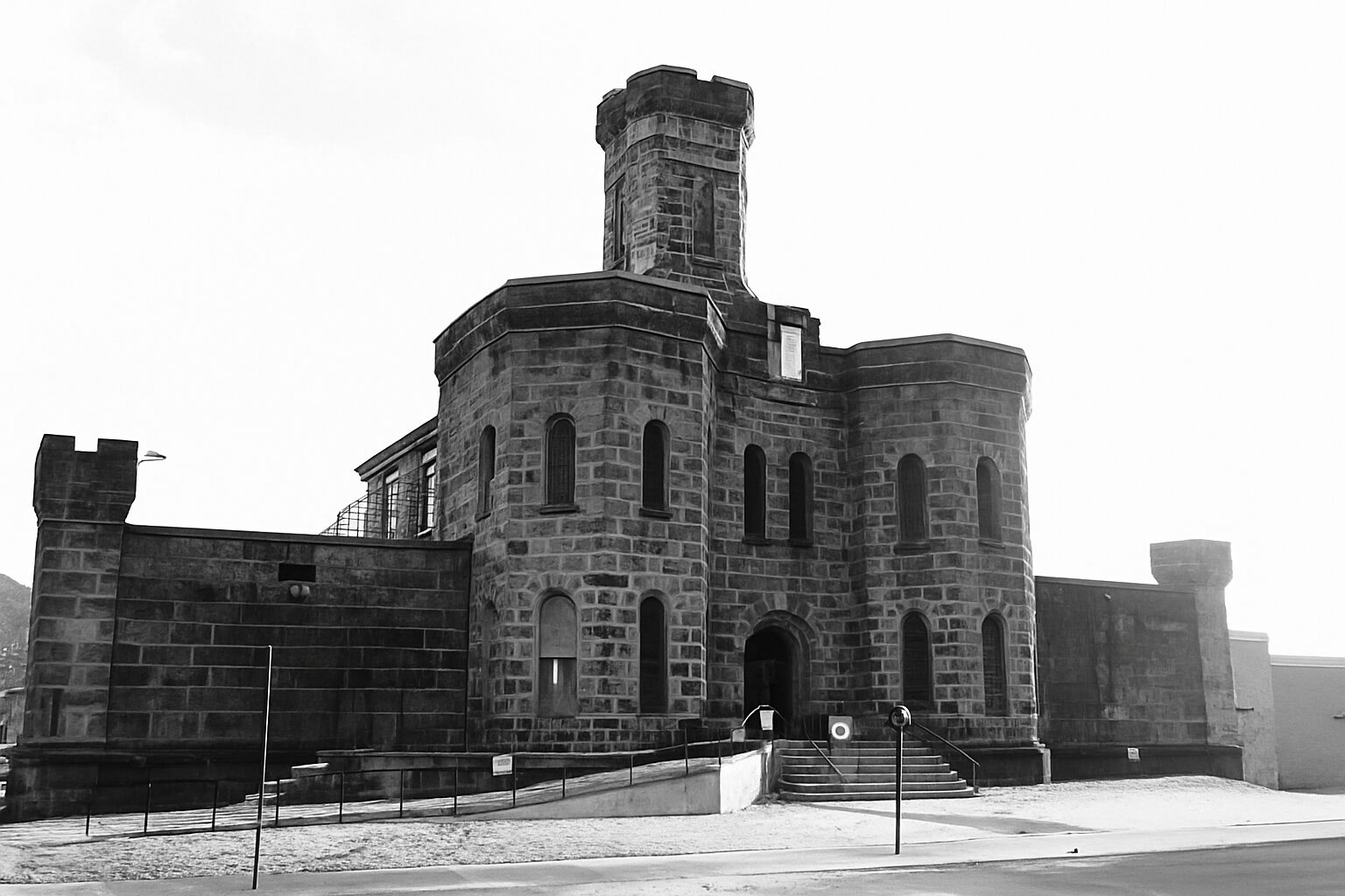 Black-and-white photograph of a historic stone prison with castle-like towers and arched windows, dramatically lit to emphasize texture and contrast, symbolizing both confinement and the possibility of redemption.